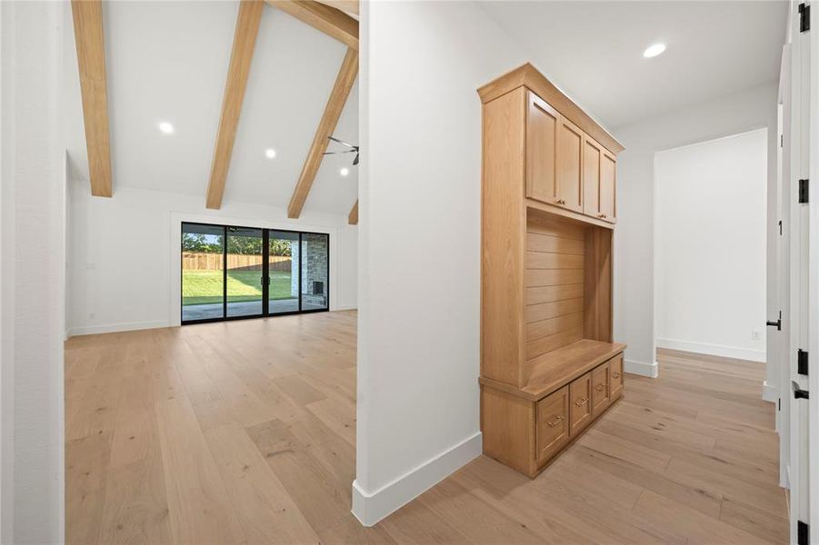 Light wood-finish flooring extending throughout, complemented by a built-in wood-finish storage unit with a bench