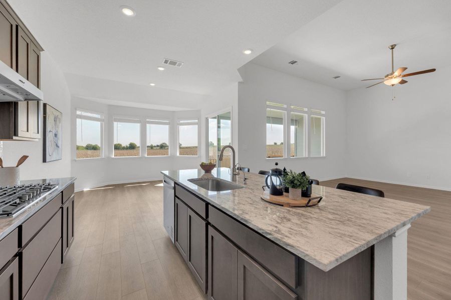 Kitchen with open floor plan, light stone countertops, light wood-style floors, stainless steel gas cooktop, and recessed lighting Kitchen with open floor plan, light stone countertops, light wood-style floors, stainless steel gas cooktop, and recessed lighting
