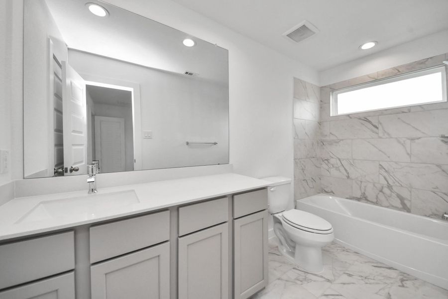 Secondary bath features tile flooring, bath/shower combo with tile surround, light stained wood cabinets, beautiful light countertop. Secondary bath features tile flooring, bath/shower combo with tile surround, light stained wood cabinets, beautiful light countertop.