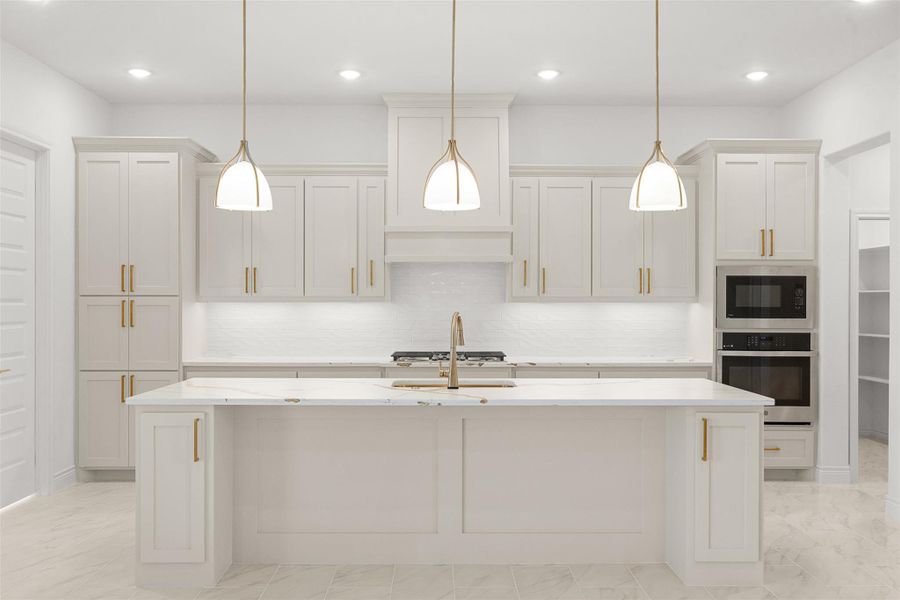 Kitchen featuring stainless steel appliances, light stone countertops, an island with sink, light marble finish flooring, and hanging light fixtures
