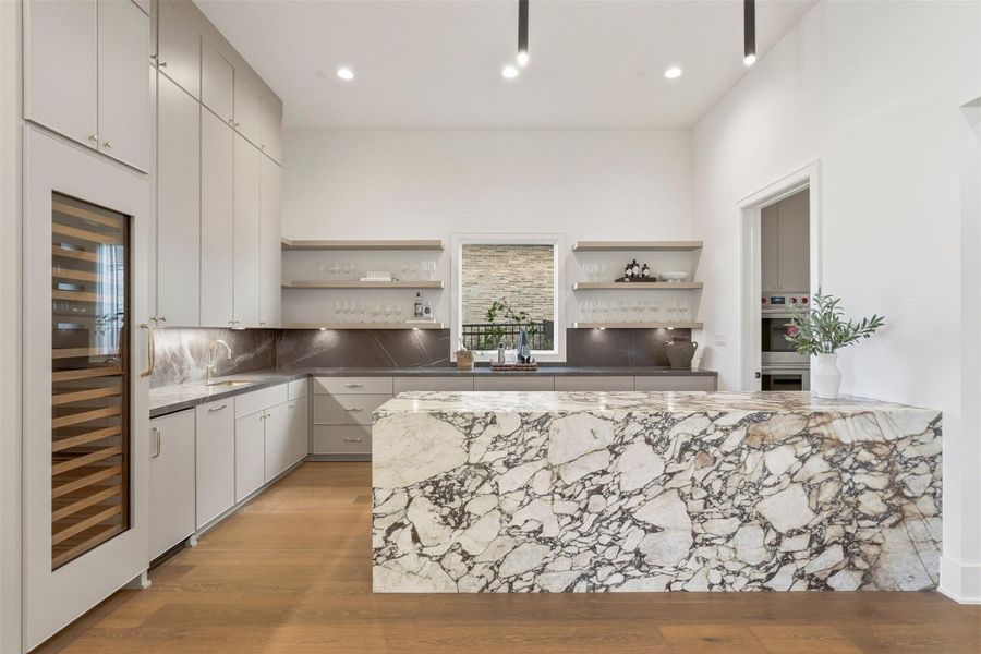 This is intentional living: a socially engineered bar that connects to the chef's pantry with a statement marble island. This fully-appointed entertaining area includes a temperature-controlled wine fridge, ample counter space, and incredible storage, creating an inviting and functional space. This is intentional living: a socially engineered bar that connects to the chef's pantry with a statement marble island. This fully-appointed entertaining area includes a temperature-controlled wine fridge, ample counter space, and incredible storage, creating an inviting and functional space.