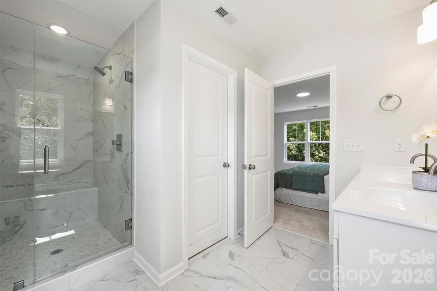 Glass enclosed shower with tiled walls in the primary ensuite.
