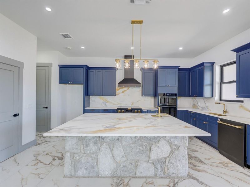 Rich blue cabinetry pairs beautifully with natural stone accents and marble-patterned surfaces throughout.