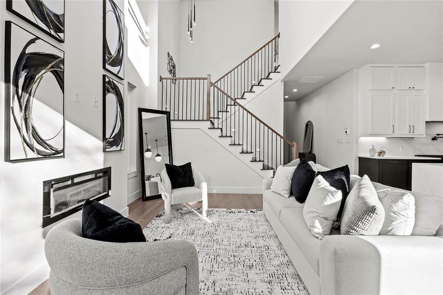 Living area with stairway, light wood finished floors, recessed lighting, and a glass covered fireplace