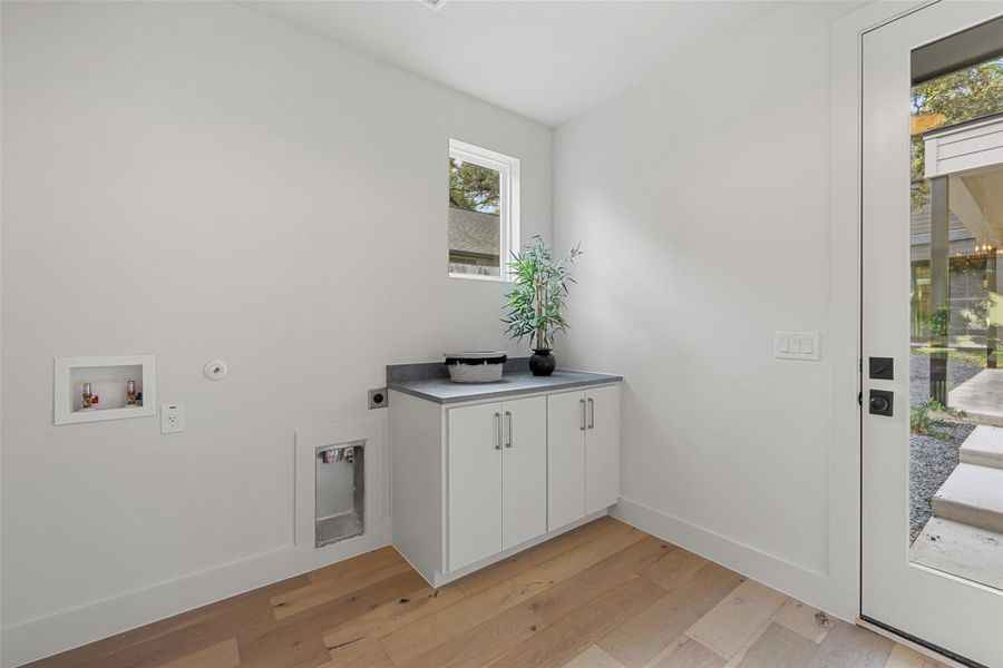 Washroom with cabinets, washer hookup, light hardwood / wood-style flooring, and electric dryer hookup