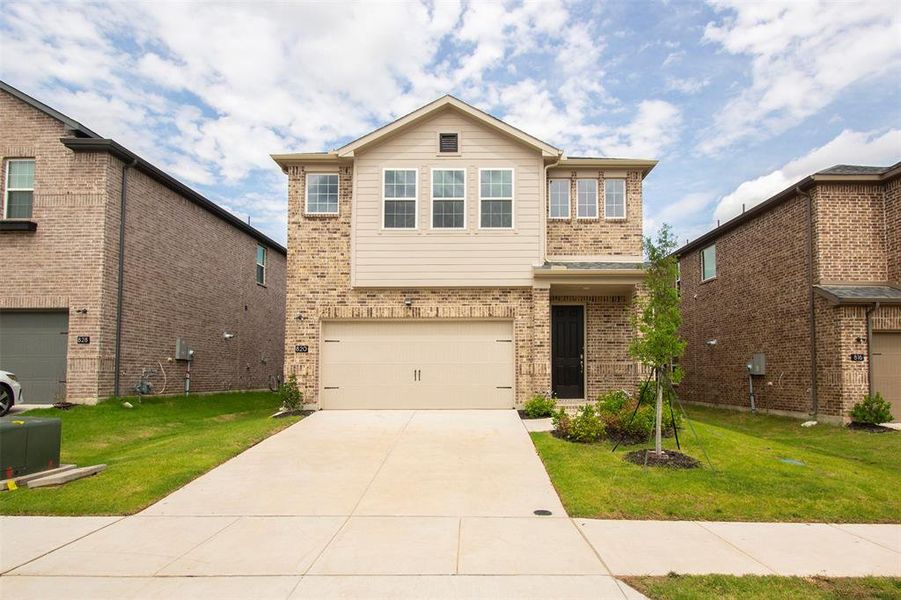 Traditional home featuring brick siding, an attached garage, driveway, and a front yard Traditional home featuring brick siding, an attached garage, driveway, and a front yard