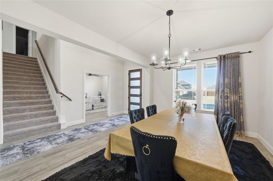 Dining space with stairs, light wood-style floors, and a chandelier