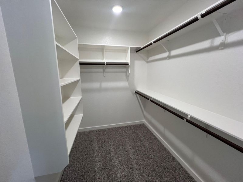 Custom built-in shelving and hanging rods offer abundant storage in this primary closet.