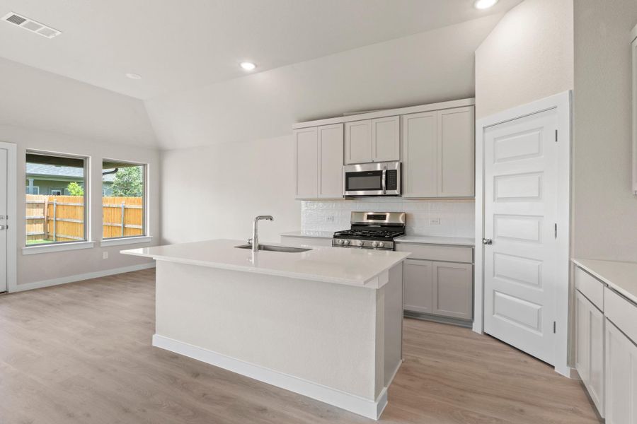 A well-lit kitchen with sleek stainless steel appliances and durable hardwood flooring.