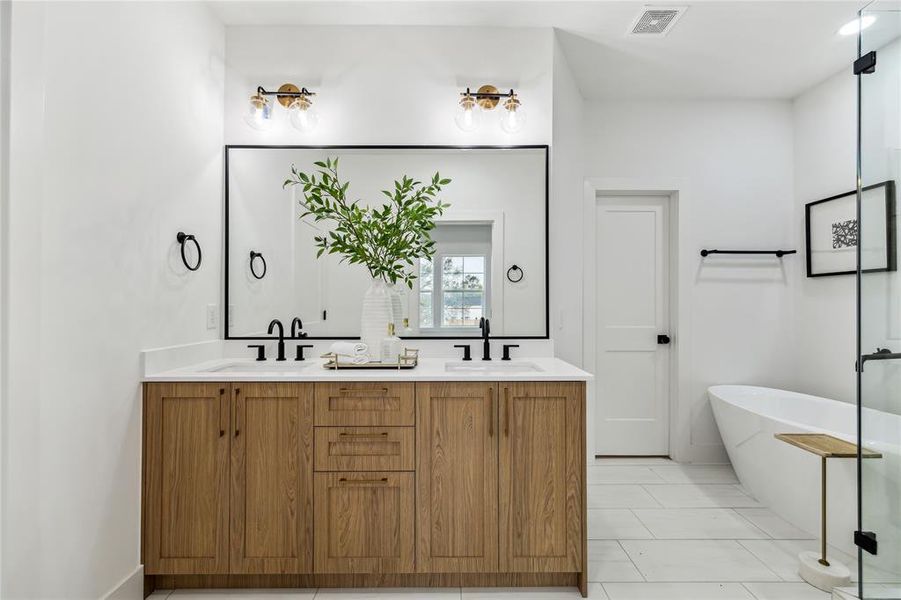 Elegant primary bathroom featuring a modern wood vanity, sleek fixtures, and a luxurious soaking tub.