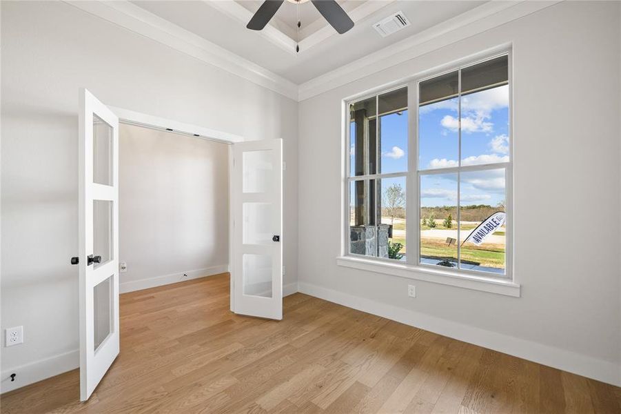 Unfurnished bedroom with light wood-style floors, crown molding, ceiling fan, and french doors