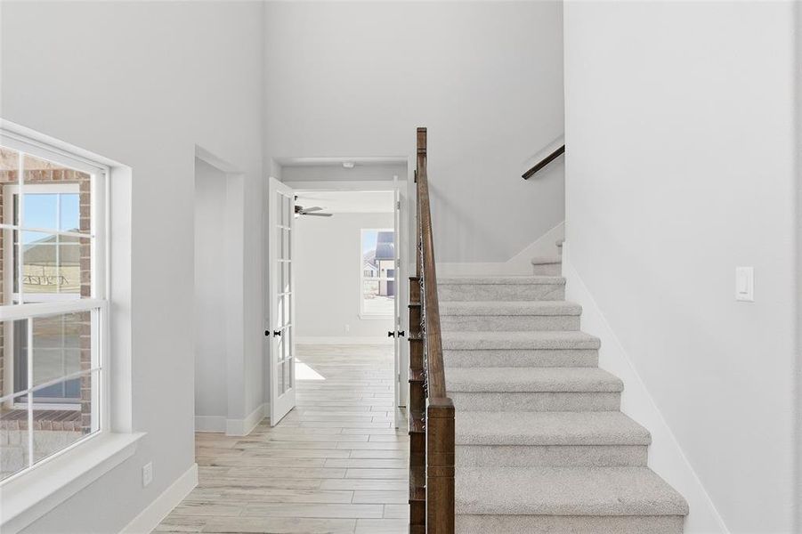 Stairway with wood finished floors and a towering ceiling