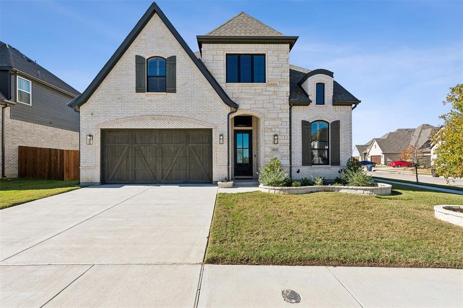 French country inspired facade with a front yard and a garage