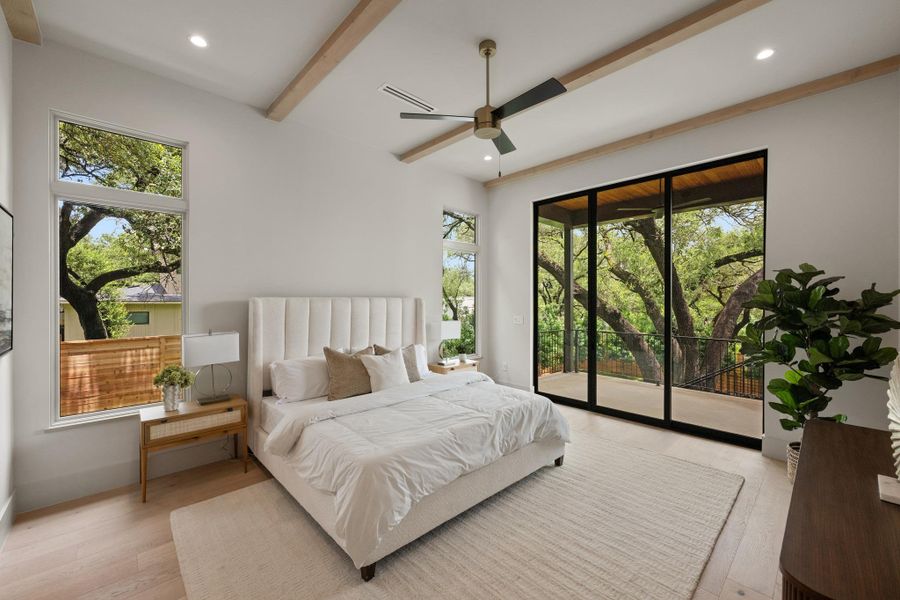 Natural light floods this primary bedroom with treetop views and access to an outdoor living space. Natural light floods this primary bedroom with treetop views and access to an outdoor living space.