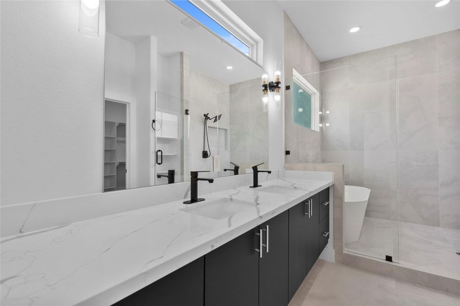Luxurious primary bathroom featuring dual vanities, a frameless glass shower, soaking tub and designer finishes throughout. Luxurious primary bathroom featuring dual vanities, a frameless glass shower, soaking tub and designer finishes throughout.