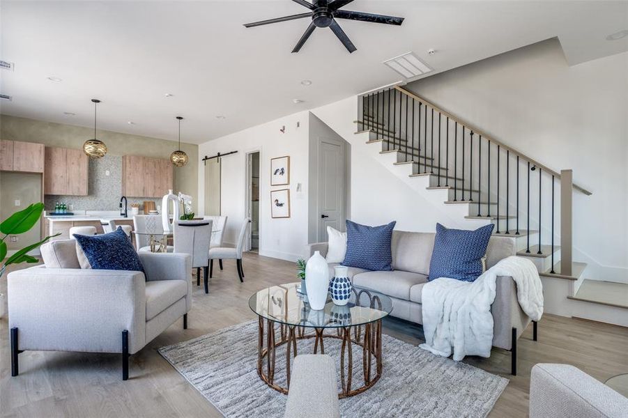 Living room featuring a barn door, light hardwood / wood-style flooring, ceiling fan, and sink