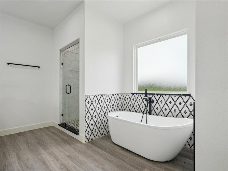 Bathroom featuring tile walls, a wealth of natural light, hardwood / wood-style floors, and independent shower and bath