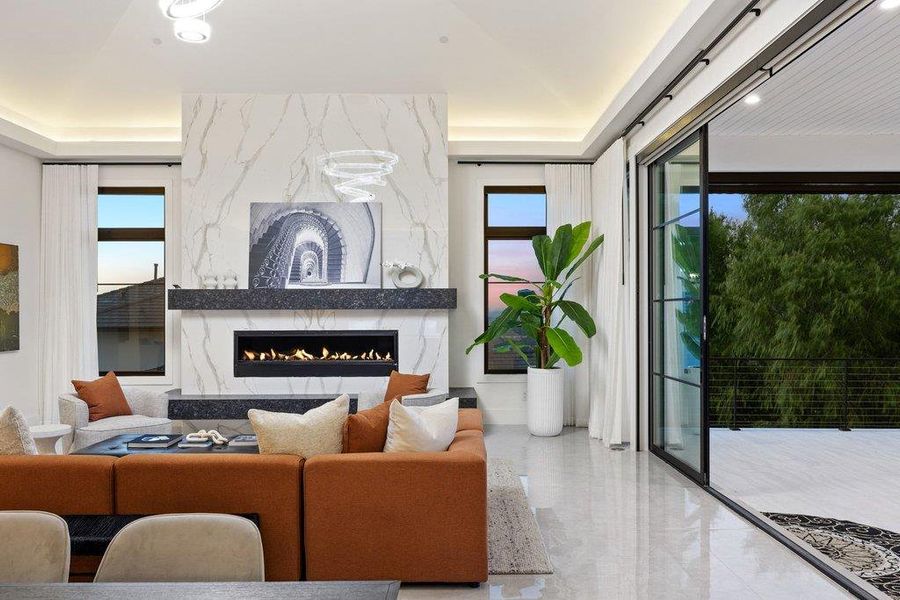 A refined living area boasts a sleek fireplace, tiled flooring, and broad sliding glass doors opening to the outdoors.