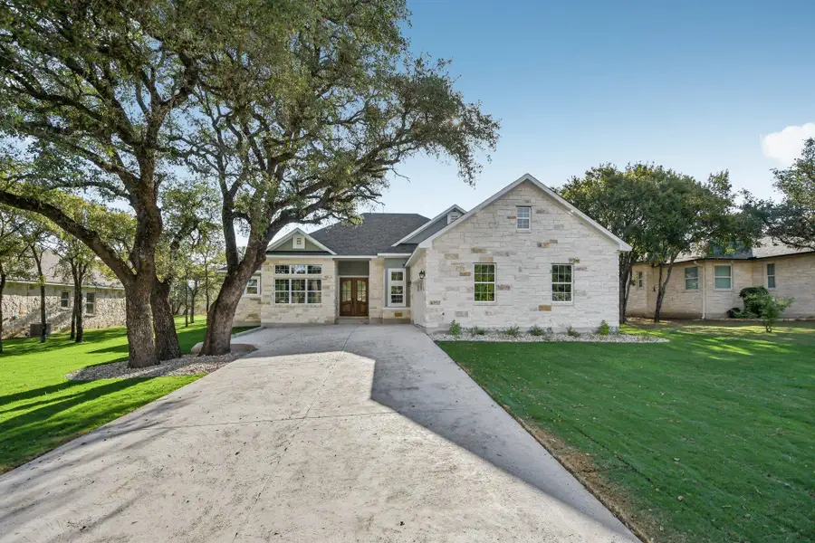 View of front of property with a front lawn, stone siding, and driveway