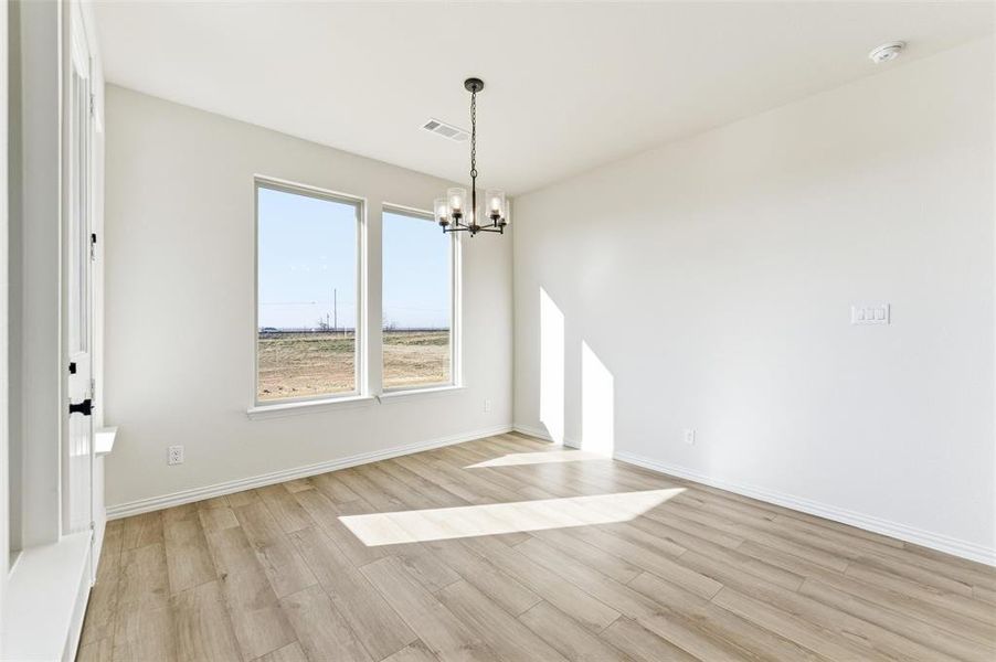 Unfurnished dining area with light wood-style flooring and a chandelier
