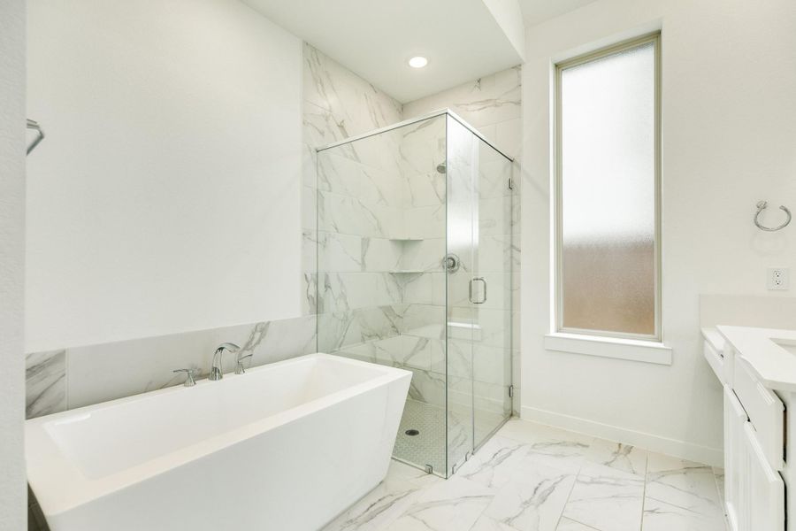 Modern primary bath featuring a luxurious soaking tub, a spacious glass walk-in shower, a private frosted window, and elegant tile flooring.