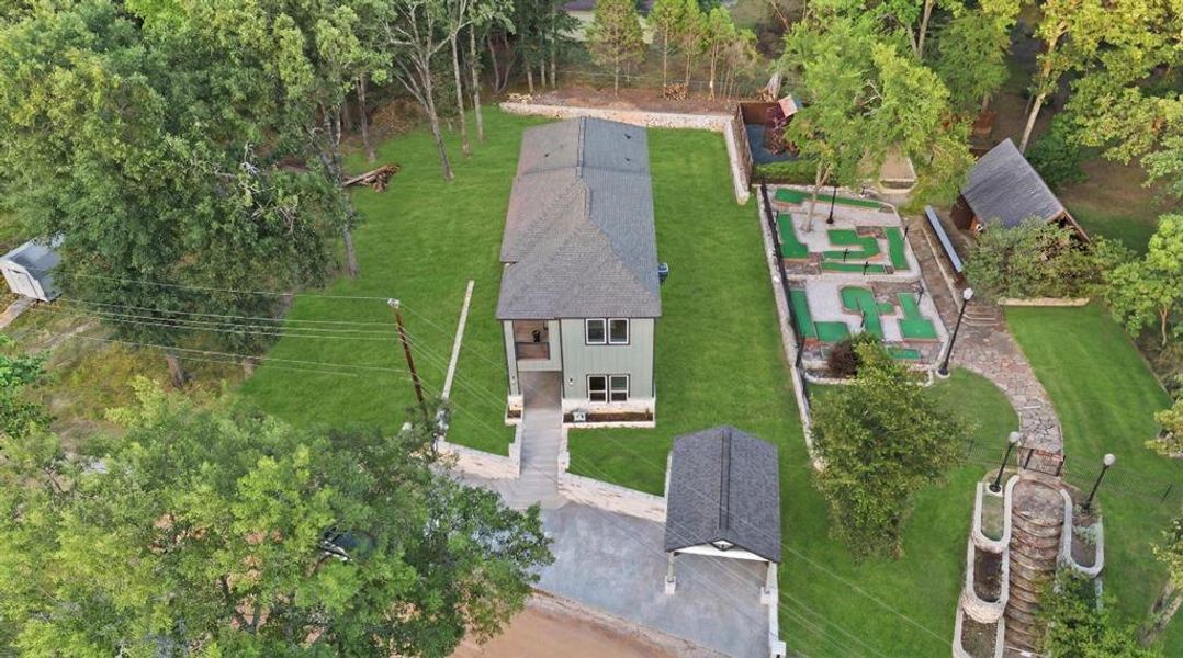 Aerial view of the property featuring a two-story residence, a detached carport, an integrated putting green, a stone pathway, and a tiered stone staircase Aerial view of the property featuring a two-story residence, a detached carport, an integrated putting green, a stone pathway, and a tiered stone staircase