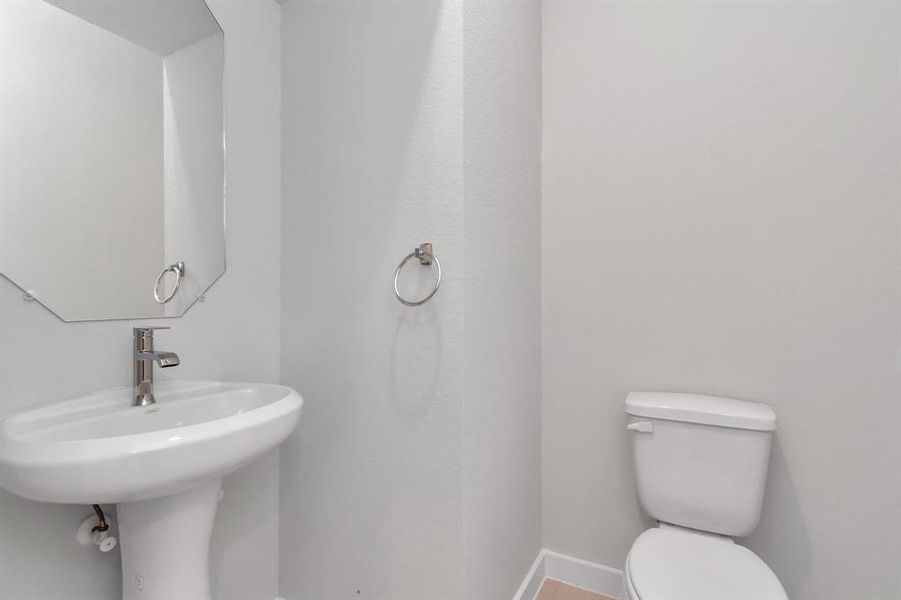 Step into this bright and airy half bath, where a sleek pedestal sink and modern hardware elevate the space with contemporary charm. Sample photo of completed home with similar floor plan. As-built interior colors and selections may vary.