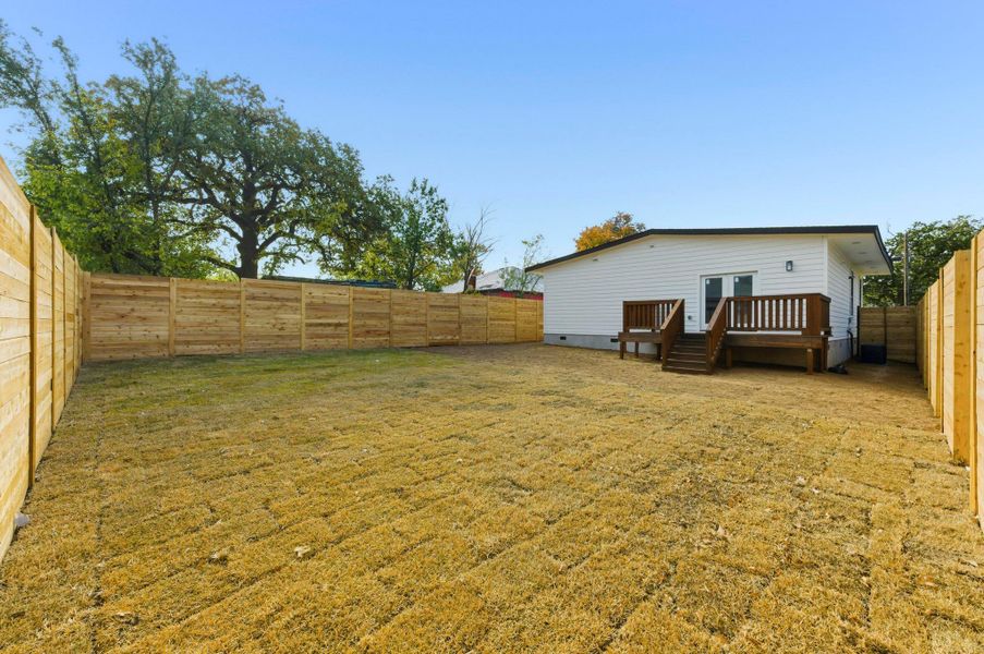 Back of property with a fenced backyard, a deck, and french doors