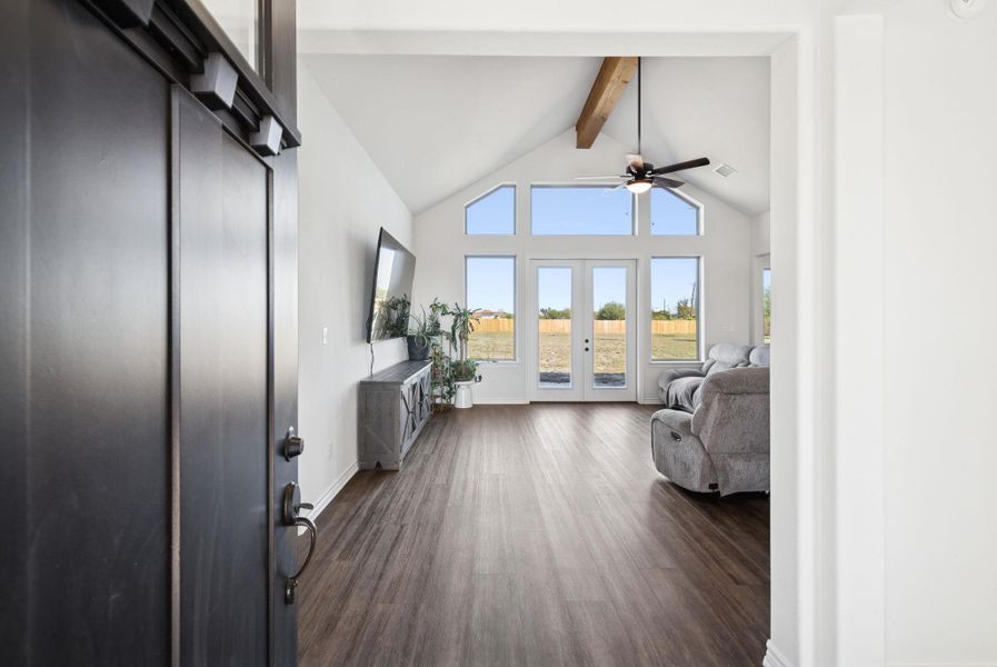 Living room featuring beamed ceiling, dark wood finished floors, high vaulted ceiling, a ceiling fan, and french doors Living room featuring beamed ceiling, dark wood finished floors, high vaulted ceiling, a ceiling fan, and french doors