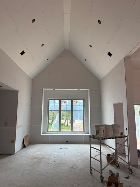 A grand, naturally illuminated living space features soaring vaulted ceilings and a large picture window.