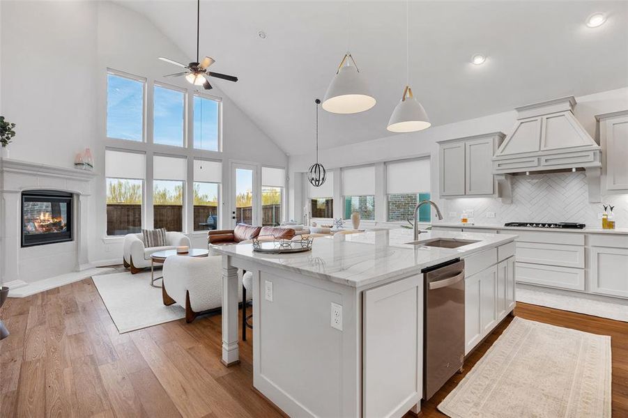 Kitchen with a sink, high vaulted ceiling, an island with sink, premium range hood, and open floor plan
