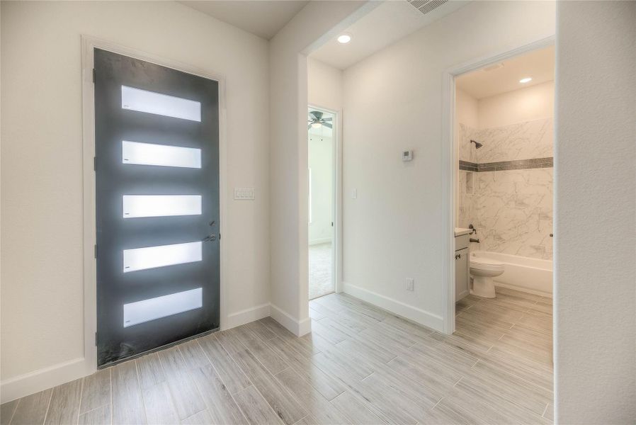 Modern entryway with a sleek black door featuring frosted glass panels.All doors in the house are 8 inches long.