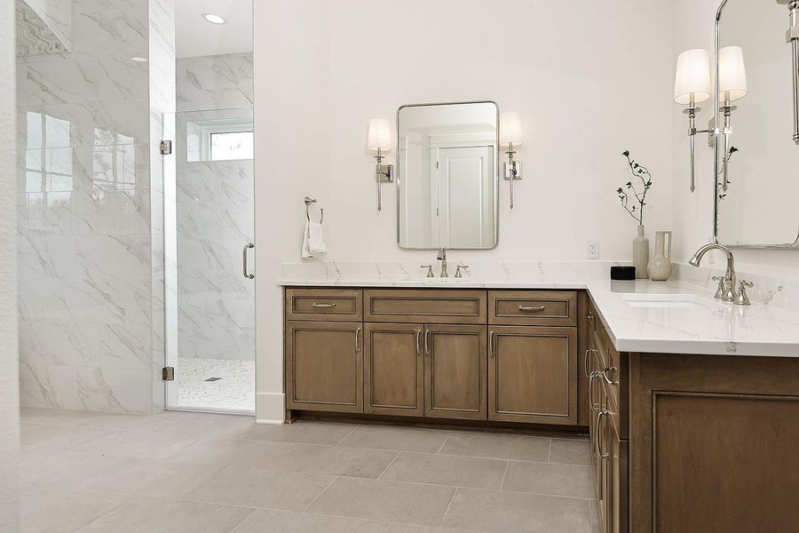 Dual vanity areas have spacious quartz counters that go beautifully with rich stained cabinetry adding warmth, character, and depth to primary bath.