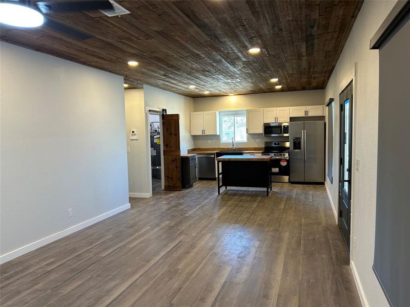 Kitchen with a barn door, white cabinetry, wood ceiling, appliances with stainless steel finishes, and dark wood-style floors Kitchen with a barn door, white cabinetry, wood ceiling, appliances with stainless steel finishes, and dark wood-style floors
