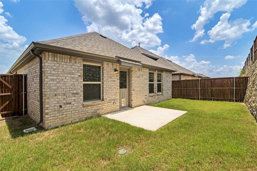Private backyard with a concrete patio, light-colored brick exterior, and a wooden privacy fence Private backyard with a concrete patio, light-colored brick exterior, and a wooden privacy fence