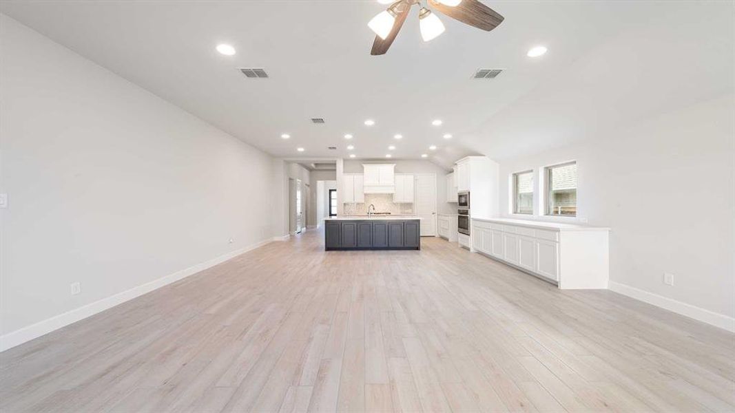 Unfurnished living room featuring lofted ceiling, ceiling fan, sink, and light hardwood / wood-style floors