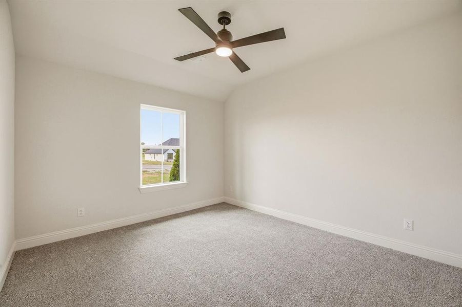 Carpeted empty room with ceiling fan and vaulted ceiling
