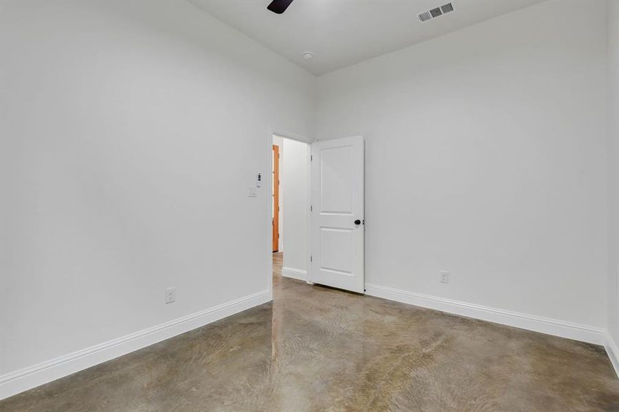 Spare room with concrete floors, ceiling fan, and a towering ceiling