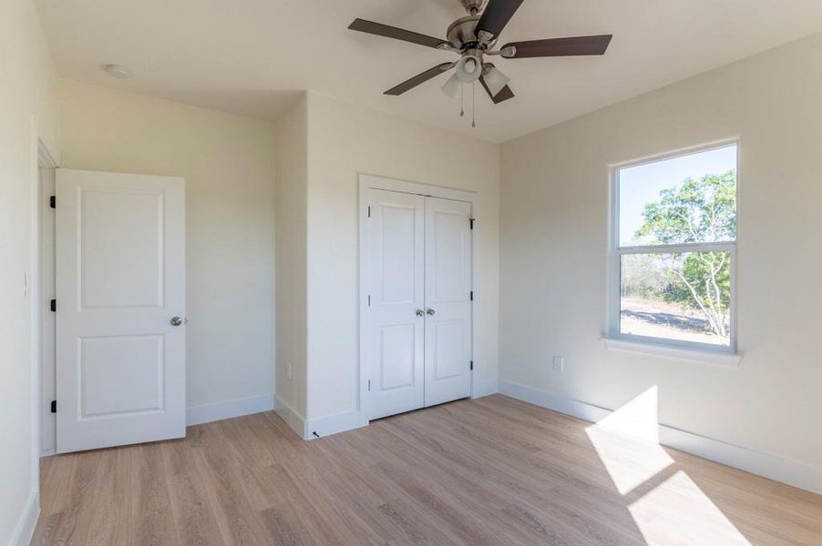 Unfurnished bedroom featuring light wood-style flooring, ceiling fan, and a closet