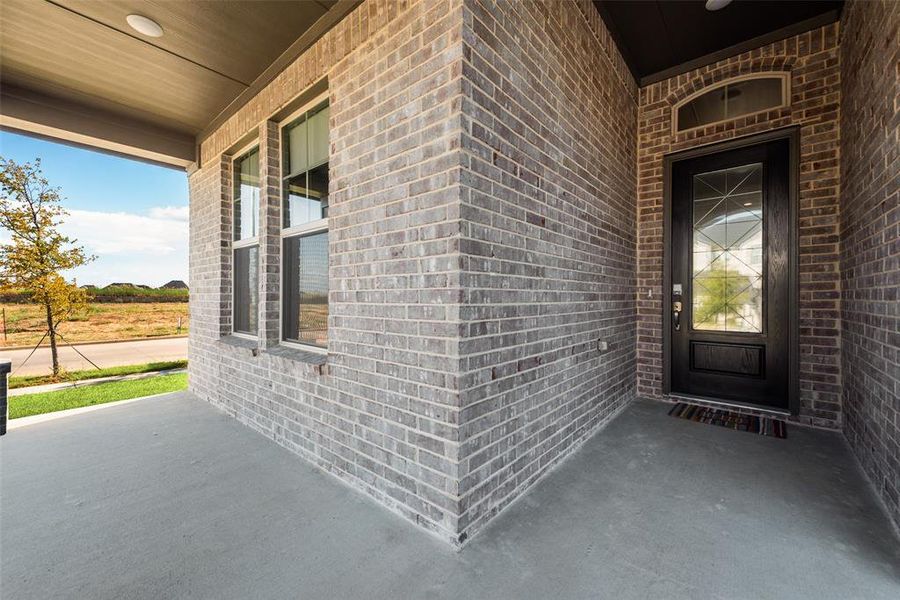 Doorway to property with a porch and brick siding