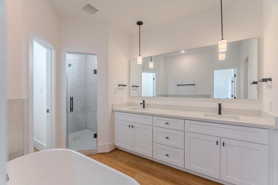 This modern bathroom features a spacious walk-in shower, a double vanity with ample storage, sleek fixtures, and elegant pendant lighting. The neutral color palette and hardwood floors add warmth and sophistication.Photo Disclaimer: Photos are representative of the community and may depict a similar floor plan, model home, or previously completed residence. This modern bathroom features a spacious walk-in shower, a double vanity with ample storage, sleek fixtures, and elegant pendant lighting. The neutral color palette and hardwood floors add warmth and sophistication.Photo Disclaimer: Photos are representative of the community and may depict a similar floor plan, model home, or previously completed residence.