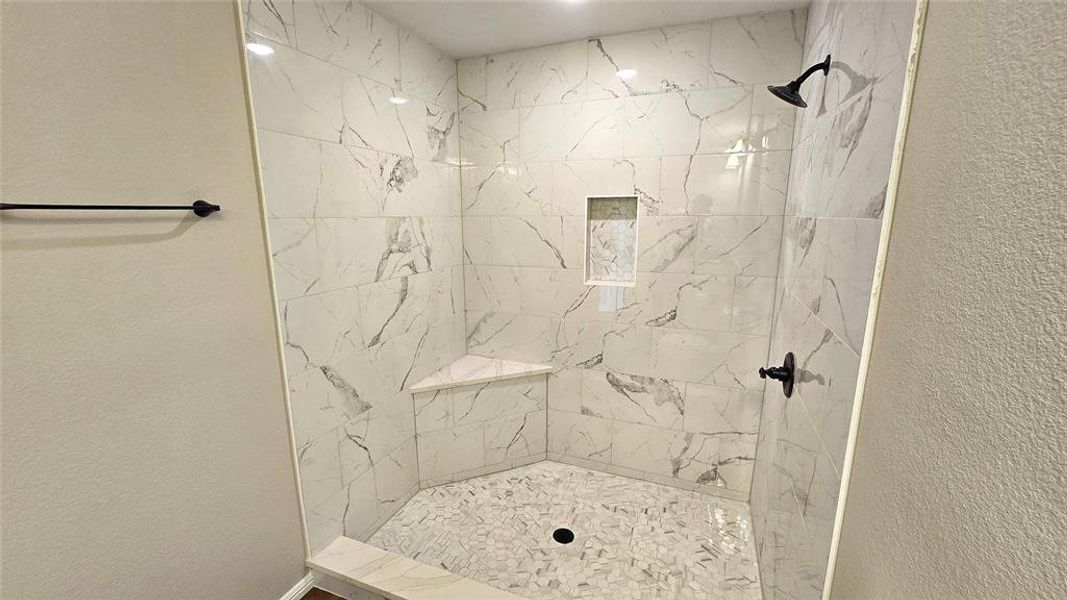 Full bathroom featuring a textured wall and a tile shower