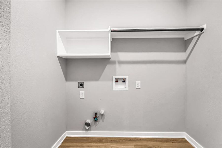 Second floor laundry room with electric or gas dryer connections as well as storage shelves and hanging rod.