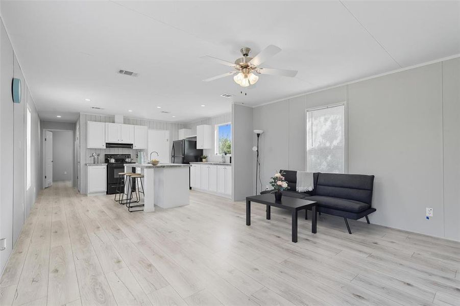 Living area featuring light wood-type flooring, ceiling fan, recessed lighting, and crown molding Living area featuring light wood-type flooring, ceiling fan, recessed lighting, and crown molding