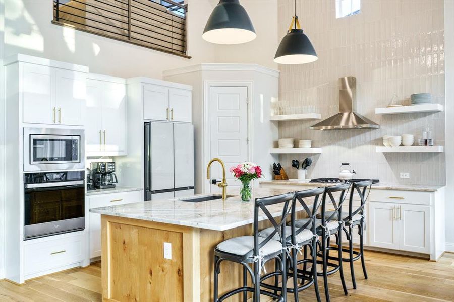 Culinary Style Meets Function - Sleek gold hardware hardware and designer pendant lights add drama to this stunning kitchen, where form meets function. A gas cooktop with a stainless steel vent hood anchors the back wall, flanked by open shelving for a modern, airy look. The natural quartzite island offers bar seating and prep space, while the four-door refrigerator delivers both innovation and visual symmetry. Culinary Style Meets Function - Sleek gold hardware hardware and designer pendant lights add drama to this stunning kitchen, where form meets function. A gas cooktop with a stainless steel vent hood anchors the back wall, flanked by open shelving for a modern, airy look. The natural quartzite island offers bar seating and prep space, while the four-door refrigerator delivers both innovation and visual symmetry.