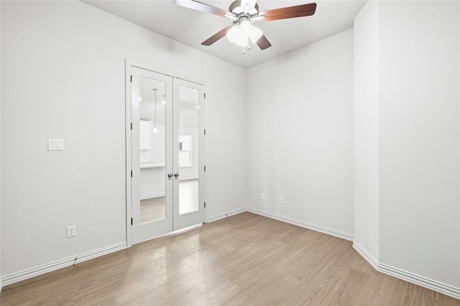 Spare room with light wood finished floors, french doors, and a ceiling fan