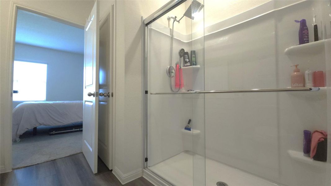 Shower stall with clear glass enclosure and built-in shelving, featuring a multi-function showerhead