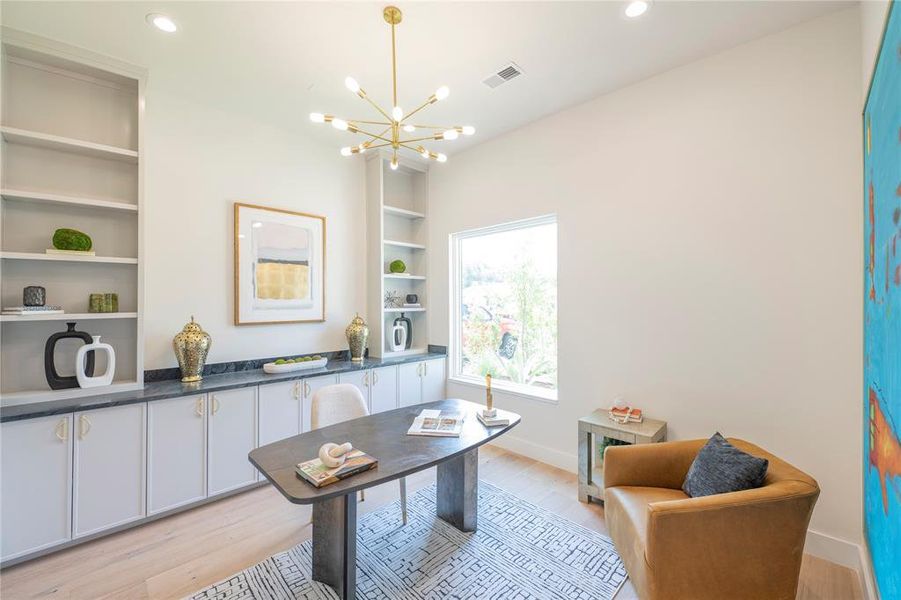 Office area featuring built in shelves, an inviting chandelier, and light wood-type flooring