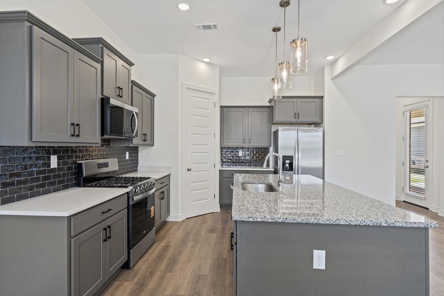 Kitchen featuring wood-finish flooring, gray cabinetry with dark hardware, white countertops, and a dark subway tile backsplash