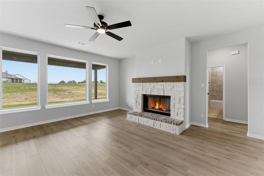 Unfurnished living room featuring ceiling fan, a fireplace, and light wood-style floors